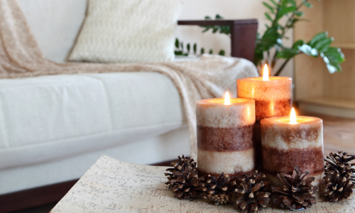 A close-up of lit candle in a living room with a couch in the background.