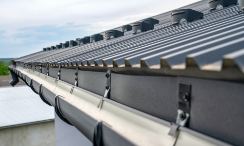 A close-up of a gutter edge of a metal roof on a clear day.